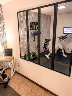 there is a bike and exercise equipment in the room with mirrors on the wall behind it