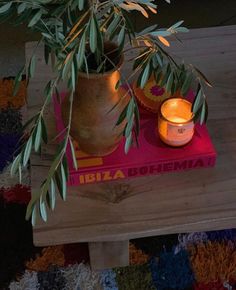 a potted plant sitting on top of a wooden table next to a lit candle