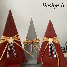 three small wooden christmas trees with bows on them, one is red and the other is gray