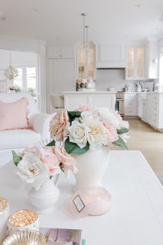 a white coffee table topped with pink and white flowers