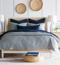 a bed with two wicker baskets on the wall above it and blue linens