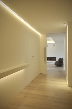 an empty room with wooden floors and white walls, illuminated by recessed lighting on the wall