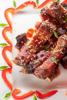 some meat is on a white plate with red peppers and green garnishes