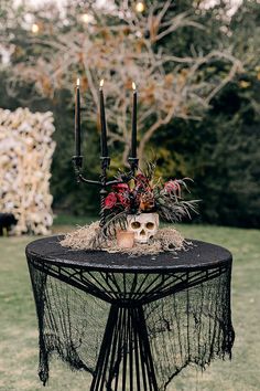 a table topped with candles and flowers on top of a lush green field covered in grass