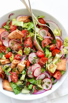 a white bowl filled with salad topped with meat and veggies next to a fork