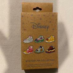 the disney mystery pin collection is in its cardboard box on top of a white surface