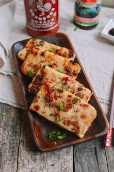 three pieces of pizza sitting on top of a wooden tray next to ketchup