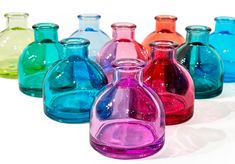 there are many different colored glass vases on the table