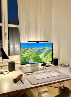 a desktop computer sitting on top of a wooden desk next to a window with white curtains