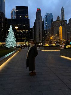 a woman is standing in the middle of a city at night with lights on her coat