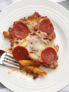 a piece of pizza on a plate with french fries and a fork next to it