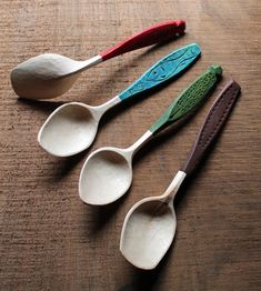 three spoons sitting on top of a table next to each other with different colored handles