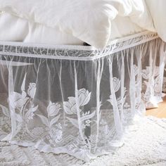 a bed with white sheets and lace on the bottom, along with a pillow case