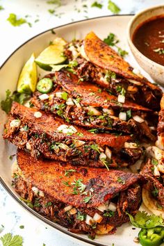 a white plate topped with ribs covered in sauce and garnished with cilantro