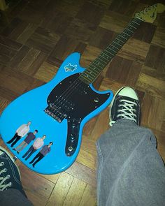 a blue guitar sitting on top of a wooden floor next to someone's feet