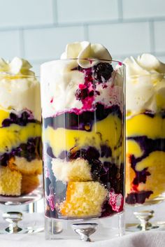 three desserts with blueberries, lemon and white frosting in glass containers on a table