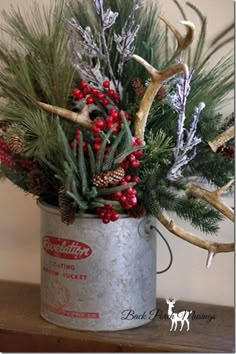 a tin can filled with evergreen, berries and deer antlers