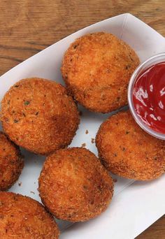 some fried chicken nuggets are on a plate with ketchup and sauce