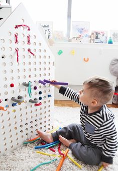 a toddler playing with peg board toys