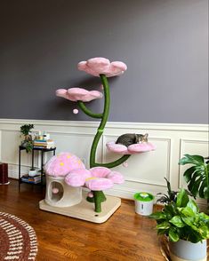 a cat sitting on top of a pink flower in a living room next to a potted plant