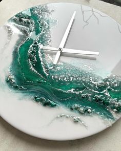 a clock made out of marble on top of a white plate with green and blue swirls