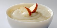 a white bowl filled with yogurt and an apple slice in the top half