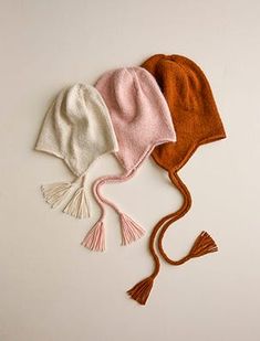 three knitted hats with tassels on them