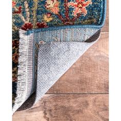 an area rug with blue and red flowers on it, laying on top of a wooden floor