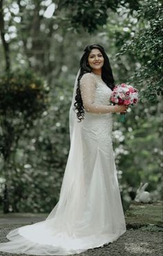 a woman in a wedding dress holding a bouquet of flowers and smiling at the camera