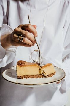 a person holding a plate with a piece of cake on it and a fork in the middle