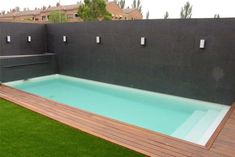 an empty swimming pool in the middle of a backyard with grass and wooden decking