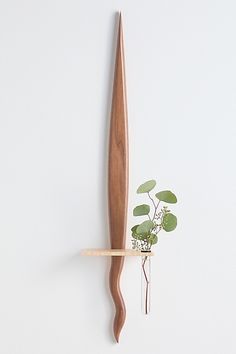 a wooden shelf with a plant on it and a long knife hanging from the wall