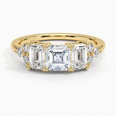 three stone diamond ring in yellow gold with diamonds on the sides and side stones around the band