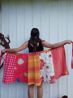 a woman is holding up some colorful towels