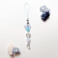 two charms are sitting next to each other on a white surface and one has a blue ribbon around it