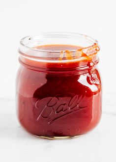 a glass jar filled with red liquid sitting on top of a white counter next to an orange peel