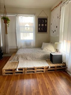 a bed made out of wooden pallets in a room with hardwood floors and windows