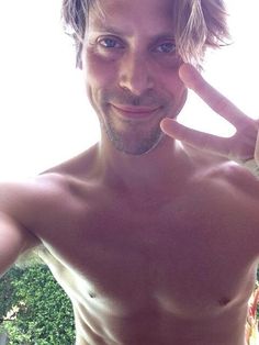 a shirtless man making the peace sign with his hand