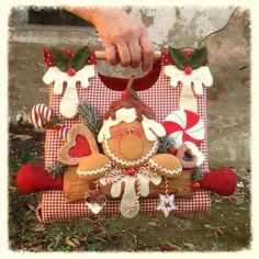 a hand holding onto a christmas decoration on top of a red and white checkered blanket