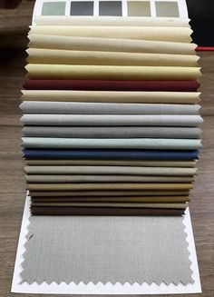 a stack of different colored fabrics sitting on top of a wooden table next to each other