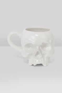 a white coffee cup with a skull design on it