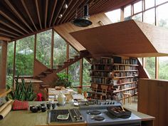 a kitchen with a stove top oven sitting under a wooden ceiling next to a bookshelf