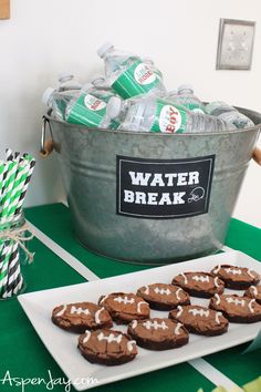 a bucket full of water and chocolate cookies on a table with green striped paper straws