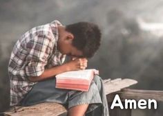 a boy is sitting on a bench with his hands clasped to his chest and looking down