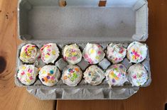 an open box filled with cupcakes on top of a wooden table