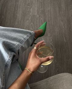 a woman holding a glass of wine with her foot up on the couch next to her