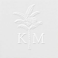 a white napkin with a palm tree on the front and k m in the middle