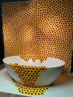 a white bowl sitting on top of a table next to a wall made out of honeycombs