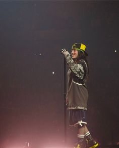 a woman standing on top of a stage with her hands in the air and holding a microphone