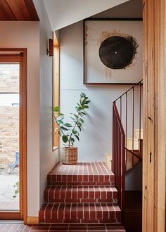 a plant in a pot sitting on the steps leading to a room with brick floors